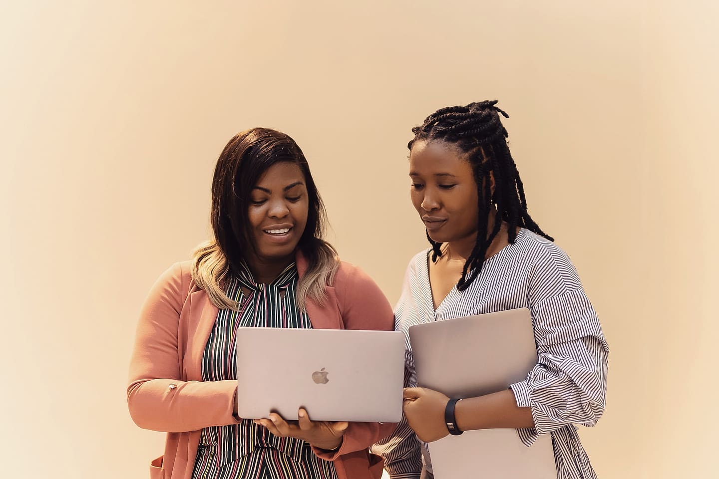 Two students standing with laptops in hand